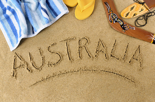 The word Australia written in sand on a beach with towel flip flops boomerang Australian summer vacation holiday photo
