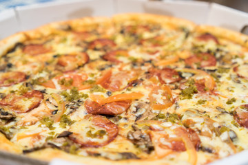 pizza with sausages, tomatoes and spinach close up view