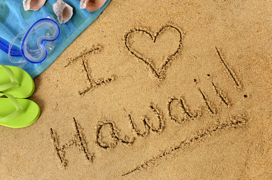 The word I Love Hawaii written in sand on a beach with towel flip flops seashells Hawaiian summer vacation holiday photo