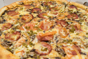 pizza with sausages, tomatoes and spinach close up view