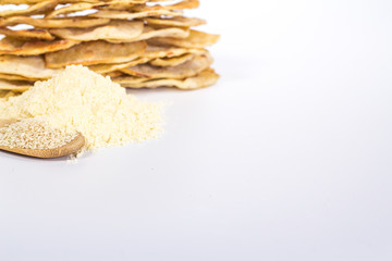 isolated stack of flat white bread, flour and spoon with sesame