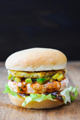 Homemade fish burger with salmon, avocado and pineapple.Close up