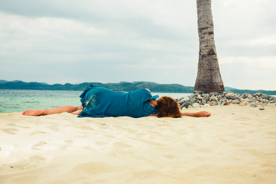 Young woman lying under palm tree on beach