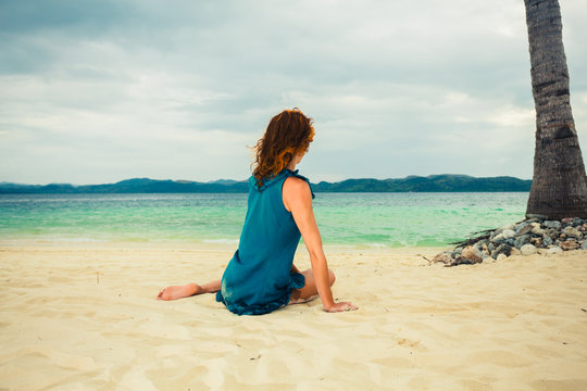 Woman sitting under palm tree on beach