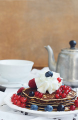 Breakfast with homemade pancakes with whipped cream and berries