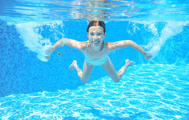 Kid swims in pool underwater, girl swimming having fun