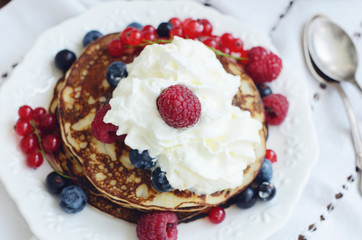 Homemade thin pancakes with whipped cream and fresh berries