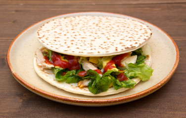Flatbread with chicken and salad on wooden table