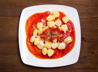 Gnocchi with tomato sauce on wooden table seen from above