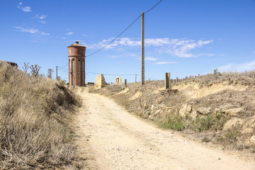 country road, blue sky,  ancient overhead water tank reserve