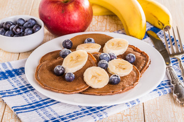 Homemade chocolate pancakes with berries and banana