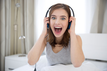 Surprised young woman with headphones at home