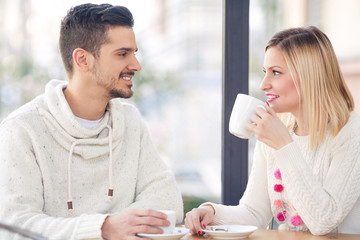 Young couple sitting in a cafe drinking coffee and tea