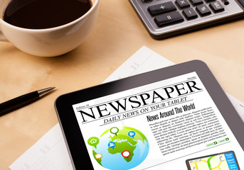 Tablet pc shows news on screen with a cup of coffee on a desk