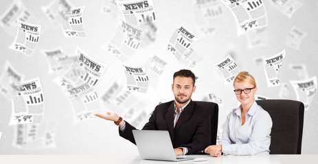 Business man and woman at desk with stock market newspapers