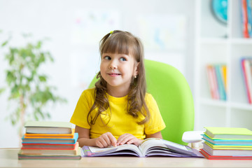 smiling child girl reading book at home