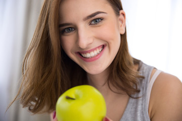 Closeup portrait of a smiling young woman with green apple