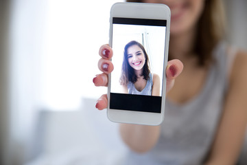 Cheerful woman making selfie photo on smartphone at home