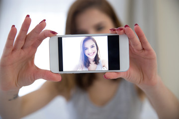 Smiling woman making selfie photo on smartphone at home