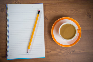Cup of coffee and notebook on a wooden.