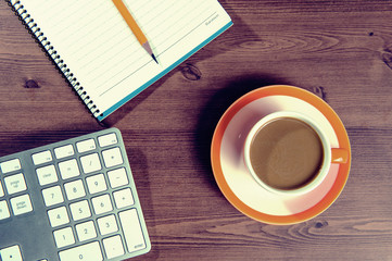 Cup of coffee and notebook on a wooden with vintage colour.