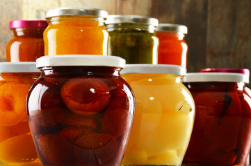 Jars with pickled vegetables, fruity compotes and jams isolated