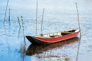 Fototapeta na wymiar Red boat on a tranquil surface of a river