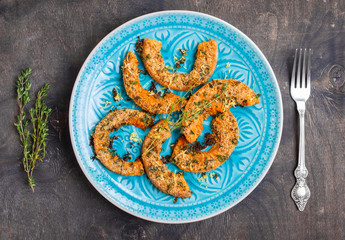 Baked pumpkin slices with herbs on wooden table in a blue bowl