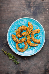 Roasted pumpkin slices with herbs on wooden table in a blue bowl