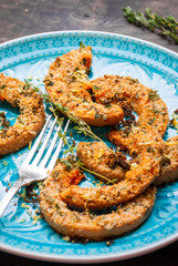 Roasted pumpkin slices with thyme in a blue bowl. Selective focu