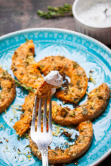 Roasted pumpkin slice with sauce on a fork. Rustic style