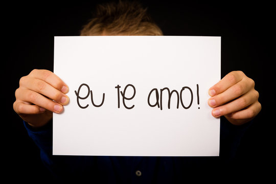 Child holding sign with Portuguese words Eu Te Amo - I Love You