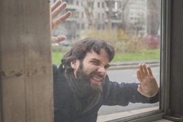 Young handsome bearded man posing behind a glass