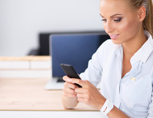 Businesswoman sending message with smartphone sitting in the