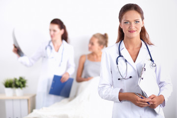 Fototapeta premium Smiling female doctor with a folder in uniform standing at