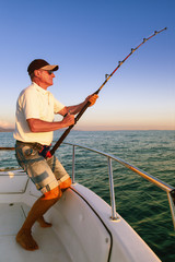 Angler fisherman fighting big fish on the ocean from the boat