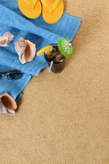Fototapeta na wymiar Beach sand background with iced cola cocktail flip flops towel and seashells summer holiday vacation photo vertical