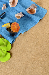Fototapeta na wymiar Beach sand background with flip flops towel cocktail and seashells summer holiday vacation photo vertical