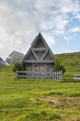 Fototapeta na wymiar Small wooden chapel in the meadows at sunrise, Giau Pass, Dolomi