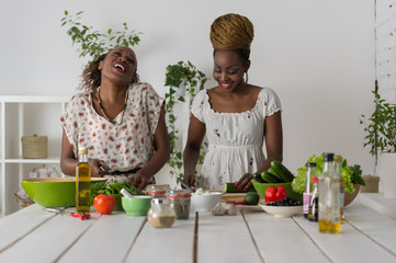 Two african women cooking salad