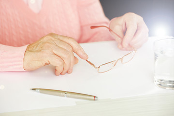 Hands of adult woman with pen, glasses and glass of water