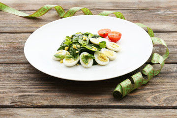 Salad with quail egg and basil in plate with measuring tape