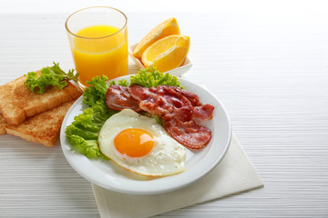 Bacon and eggs on color wooden table background