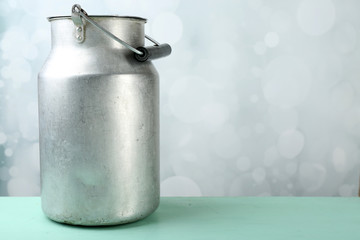 Retro can for milk on wooden table on light background