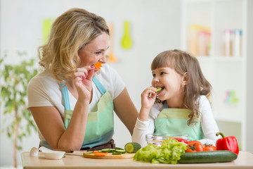 kid girl and mother eating healthy food vegetables