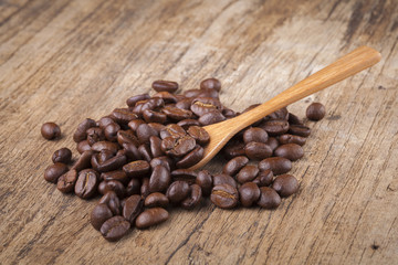 roasted coffee beans in wooden spoon placed on coffee beans as b