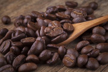 roasted coffee beans in wooden spoon placed on coffee beans as b