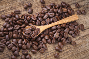 roasted coffee beans in wooden spoon placed on coffee beans as b