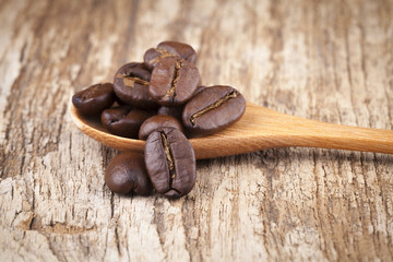 roasted coffee beans in wooden spoon placed on coffee beans as b
