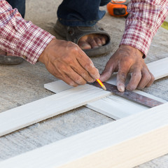 Fototapeta na wymiar carpenter using ruler to draw a line marking on a wood board